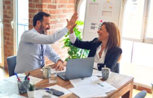 Eerste medewerker aannemen: ondernemer geeft high five aan collega